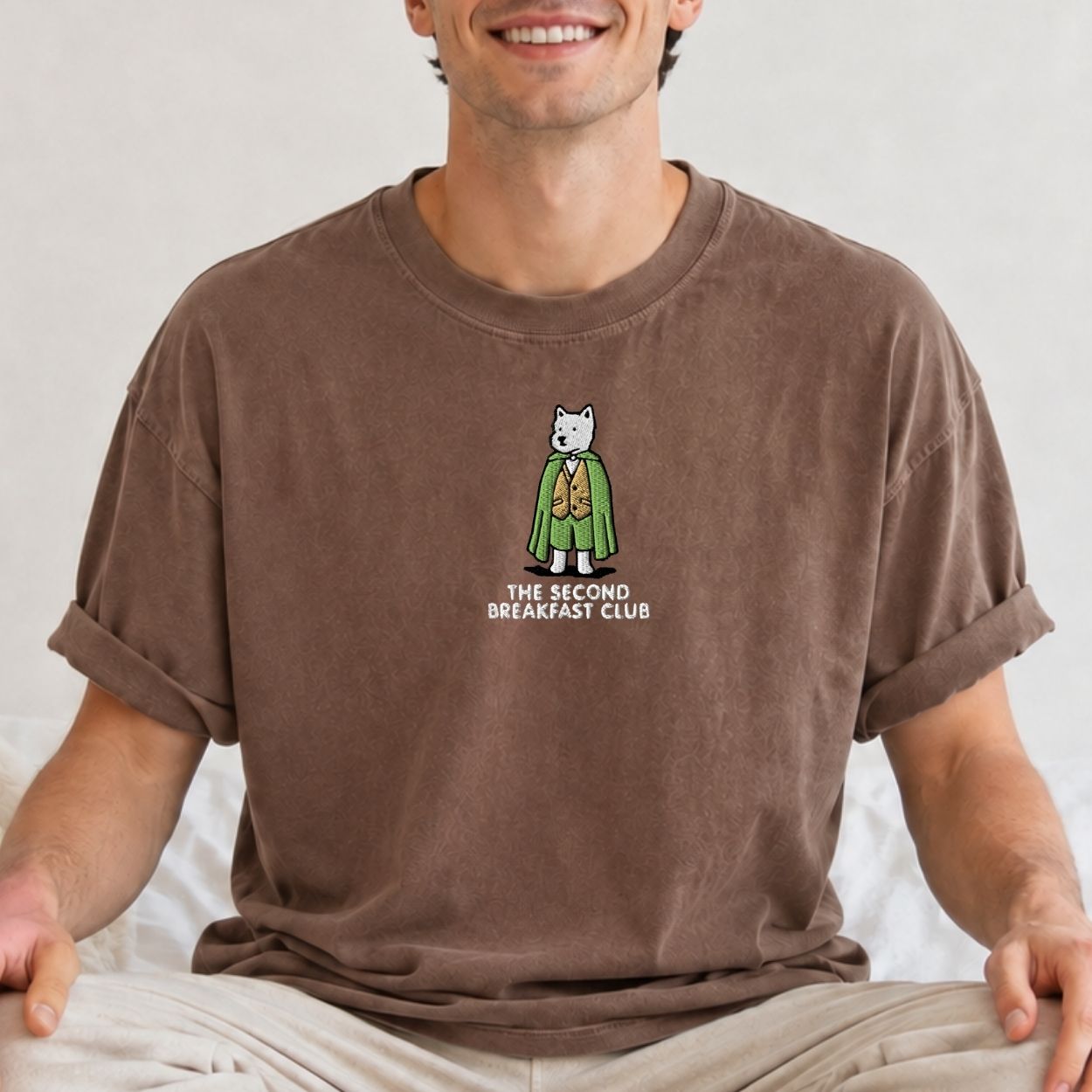 A man wearing a brown t-shirt with a graphic of a dog in a green cape and the text 'THE SECOND BREAKFAST CLUB'.